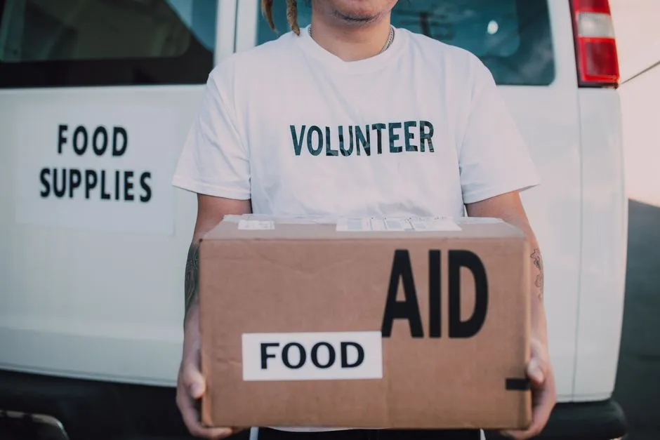 Volunteer handing over a box of food aid at a distribution site