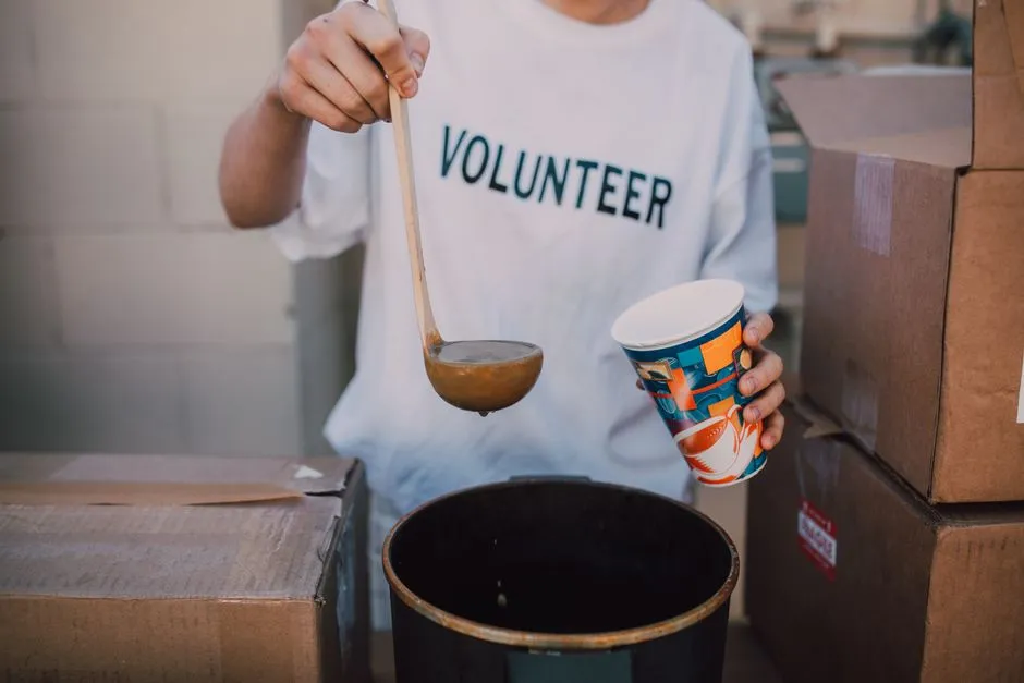 Volunteer ladling hot soup into a bowl at a community meal program